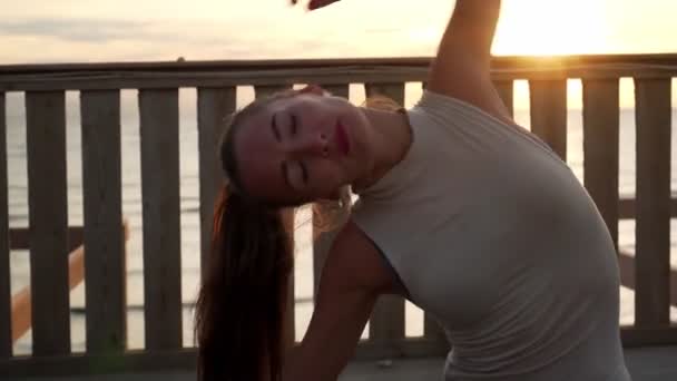 Закройте гибкую кавказскую девушку, растянувшуюся в бечевке на крыше на рассвете. — стоковое видео