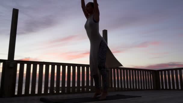 Joven chica caucásica practicar yoga en la azotea en la puesta de sol de colores brillantes — Vídeos de Stock