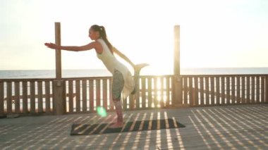 Esnek Kafkasyalı kız güneş ışığında çatıda yay yoga pozu veriyor.