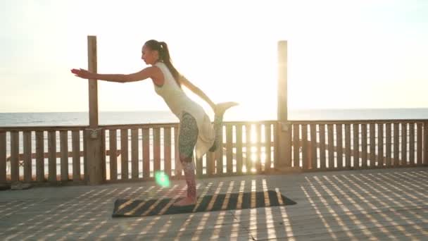 Esnek Kafkasyalı kız güneş ışığında çatıda yay yoga pozu veriyor. — Stok video