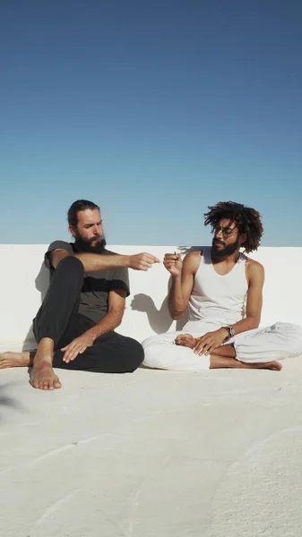 Çok ırklı arkadaşlar çatıdaki mavi gökyüzünde ot içiyorlar.