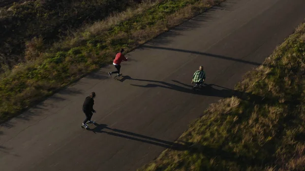 Luftaufnahme von drei Hipster-Männern Skateboard fahren schnell auf Sunset Road Drohne — Stockfoto