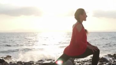 Athletic young woman doing a work out at seashore at sunset