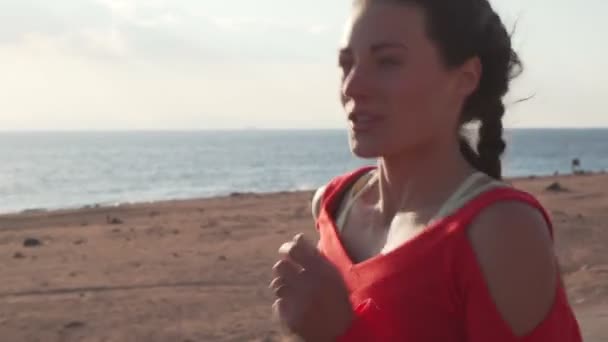 Atletisch mooi meisje lopen op promenade bij zonsondergang in de buurt van oceaan — Stockvideo