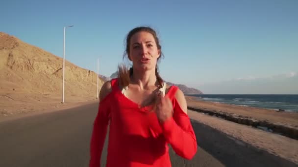 Portret ładnej dziewczyny biegającej po morzu w zwolnionym tempie o zachodzie słońca — Wideo stockowe