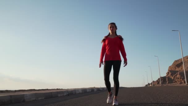 Young motivated girl is preparing to run on promenade at sunsetin nature — Stock Video