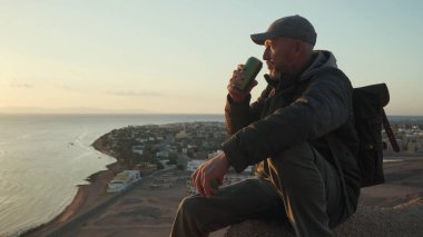 Kıdemli gezgin, termofonu aç ve bir tepede otururken sıcak bir şeyler iç.