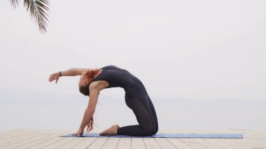 Sisli gündoğumunda denizde hatha yoga yapan güzel bir kadın.