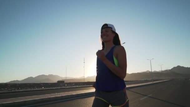 Sourire caucasien fille jogging à l'autoroute dans montagnes rapide ralenti — Video