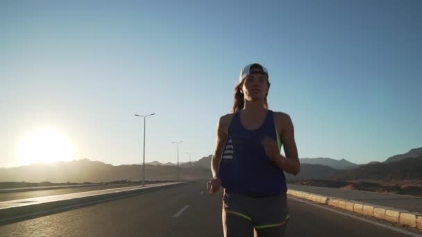 Slim caucasian girl jogging at highway in mountains rapid slow motion — Stock Video