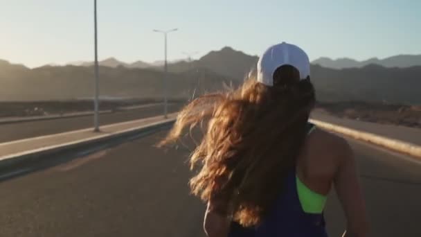 Vue arrière de la jeune fille mince jogging à l'autoroute dans les montagnes au ralenti rapide — Video