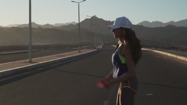 Νεαρό κίνητρο κορίτσι κάνει άλματα άσκηση κατά τη διάρκεια του τζόκινγκ στην εθνική οδό το ηλιοβασίλεμα — Αρχείο Βίντεο