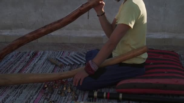Bearded man playing didgeridoo ustralian instrument on rooftop at sunrise — Stock Video