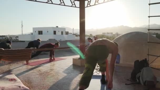 DAHAB, EGYPT 24.02.2020 - Grupul de începători fac yoga în timp ce bărbatul joacă didgeridoo — Videoclip de stoc