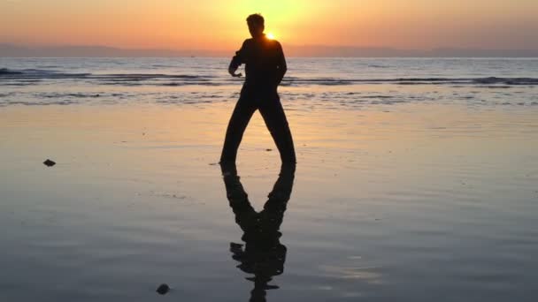 El hombre hace prácticas energéticas en la superficie reflejada de las aguas poco profundas del atardecer — Vídeos de Stock