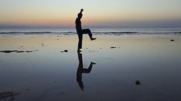 Deniz kıyısındaki insan yansıması gün batımında qigong egzersizleri yapıyor. — Stok video