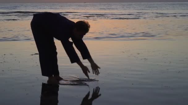 Silhouet van de mens die Qigong oefeningen beoefent werkend met energie aan zee — Stockvideo