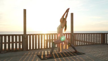 Esnek Kafkasyalı kız çatıda gün ışığında savaşçı yoga pozu veriyor..