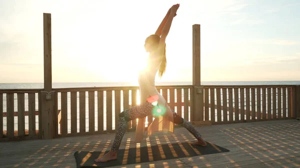 Flexible caucásico chica práctica guerrero yoga pose en la azotea en sol . —  Fotos de Stock