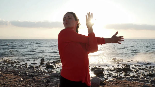 Mujer en la orilla del mar estirándose antes del entrenamiento —  Fotos de Stock