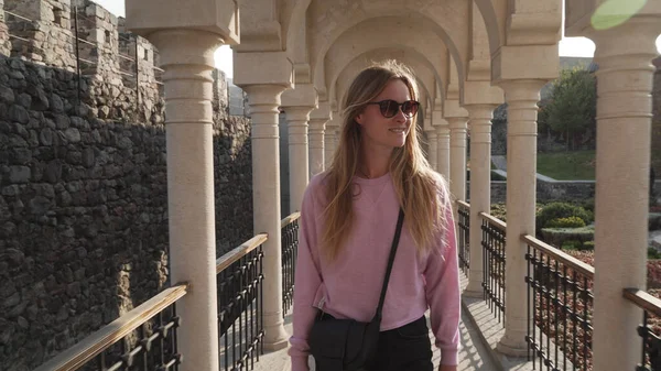 Ortaçağ şatosunda yürüyen sarışın, beyaz bir kadının portresi.