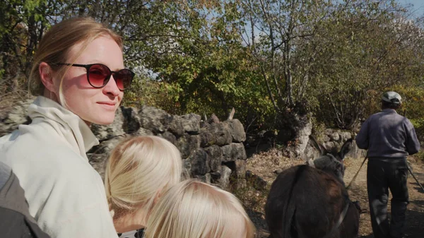 young mother with daughters ride on a donkey-drawn cart