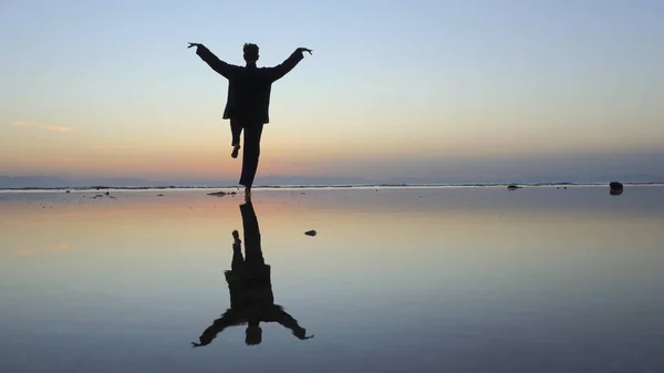 Silueta del hombre practicando ejercicios de qigong al atardecer junto al mar —  Fotos de Stock