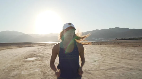 Genç beyaz kız gün doğumunda kuru çölde koşuyor..