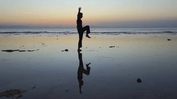 Silueta del hombre practicando ejercicios de qigong al atardecer junto al mar —  Fotos de Stock