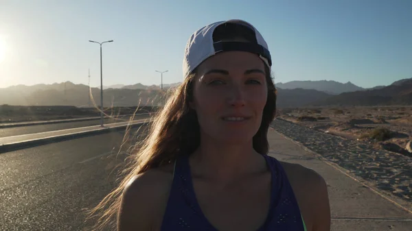 Gün batımında otoyolda kameraya gülümseyen bir kız.