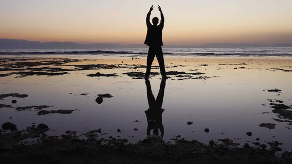El hombre practica ejercicios de qigong, figura reflectante de aguas poco profundas . —  Fotos de Stock