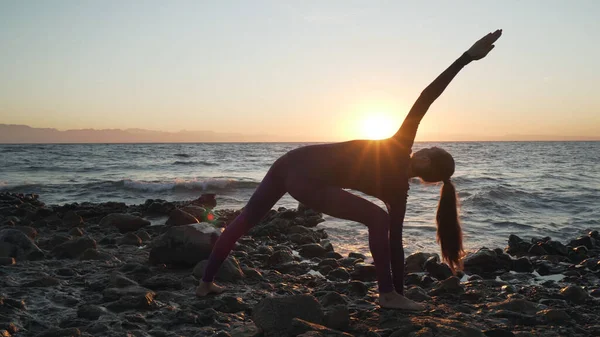 Chica caucásica flexible practicando yoga en la orilla del mar por la mañana . —  Fotos de Stock