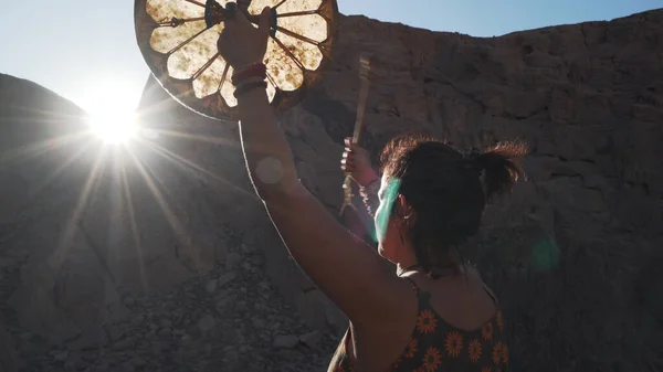 Tanınmayan bir kadın güneşin altında tef çalıyor. Gün batımında güneş parlıyor..