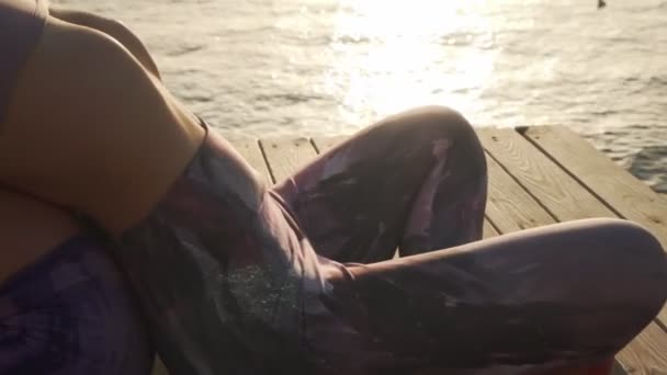 Close up zwei Mädchen üben sitzend vor und zurück beugt Yoga-Haltung bei Sonnenuntergang — Stockvideo