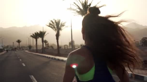 Zadní pohled na mladé brunetky dívka jogging na tropické dálnici na slunci — Stock video