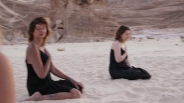 Bir grup kadın kumlu çölde meditasyon yapıyor.