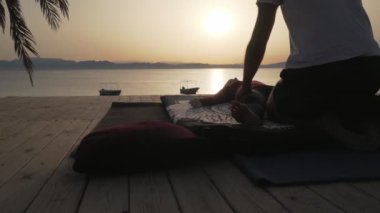 Gün batımında bir kadın için masaj yapan siluet insan.