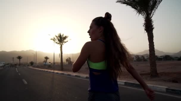 Jogger girl pára para respirar na estrada tropical ao pôr-do-sol câmera lenta — Vídeo de Stock