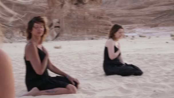 Bir grup kadın kumlu çölde meditasyon yapıyor. — Stok video
