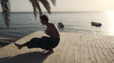 Esnek Kafkas adam güneş ışığında deniz kenarında yoga egzersizi yapıyor.