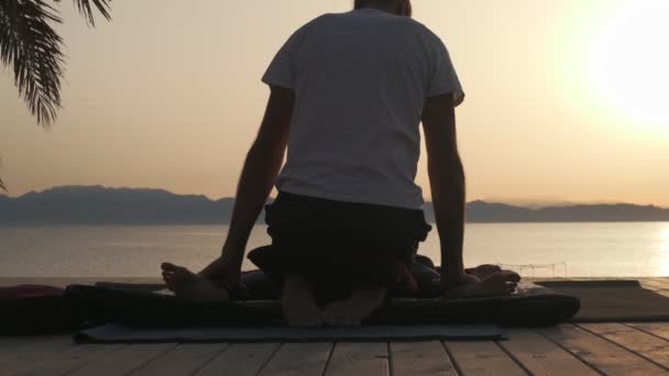 Visão traseira pessoa fazendo massagem para uma mulher na praia do pôr do sol — Vídeo de Stock