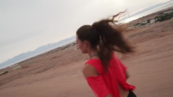 Bruneta dívka jogging podél silnice na pobřeží dynamické aktivní pohyb fotoaparátu — Stock video