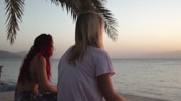 La silueta de las mujeres se estira antes de practicar yoga a la orilla del mar al atardecer — Vídeos de Stock