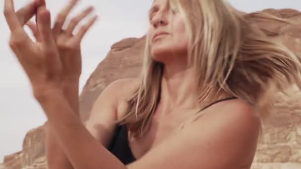 Портрет блондинки в черном костюме практикует экстатический танец в пустыне — стоковое видео