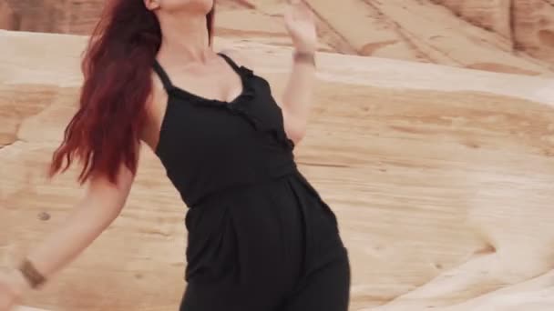 Beautiful redhead girl in black suit practice ecstatic dance in sandy desert — Stock Video