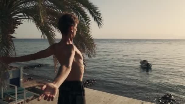 Hombre caucásico flexible practicando yoga a la orilla del mar al amanecer — Vídeo de stock
