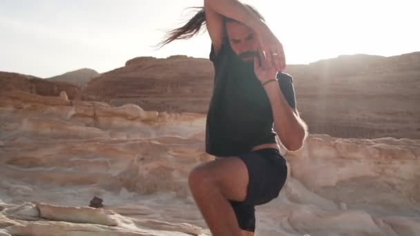 Knappe man oefenen extatische dans in de woestijn in de zon snelle slow motion — Stockvideo