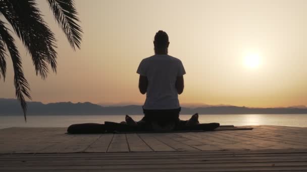 Bakre vy man gör thai yoga massage för en kvinna vid soluppgången stranden — Stockvideo