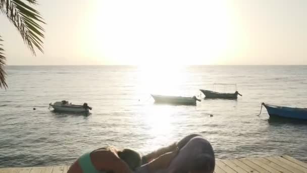 2人の女性練習パートナーヨガ姿勢で海辺で太陽 — ストック動画