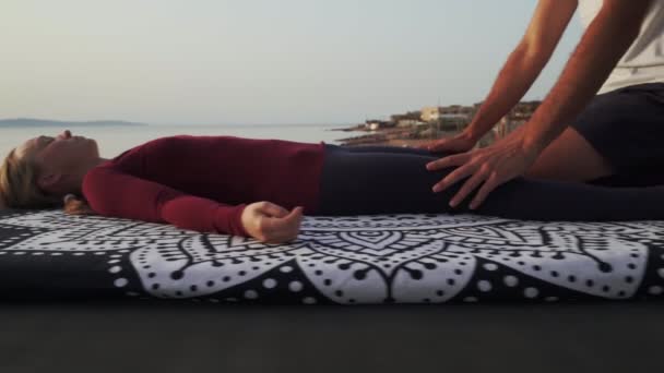 Закройте руки, делая массаж для женщины на берегу заката — стоковое видео